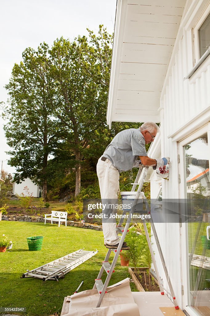 Senior man painting house