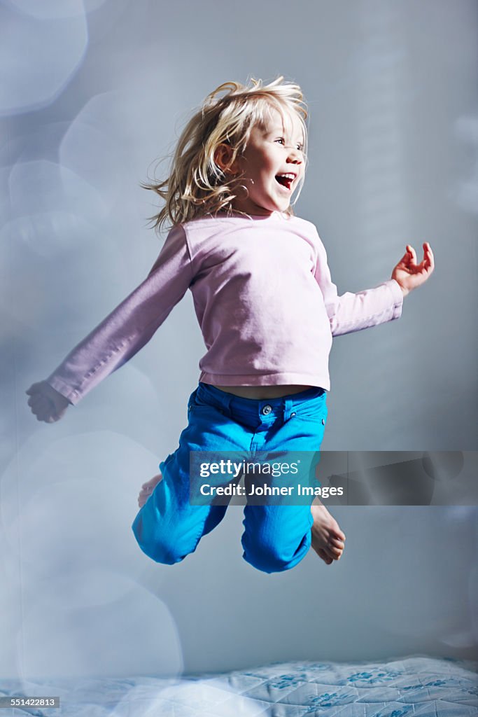 Girl jumping on bed