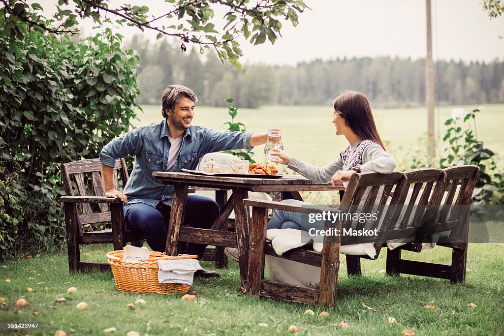 Couple serving water to woman at breakfast table in organic farm