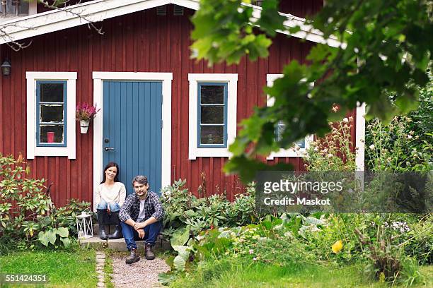 mid adult couple sitting outside farmhouse - farmhouse stock pictures, royalty-free photos & images