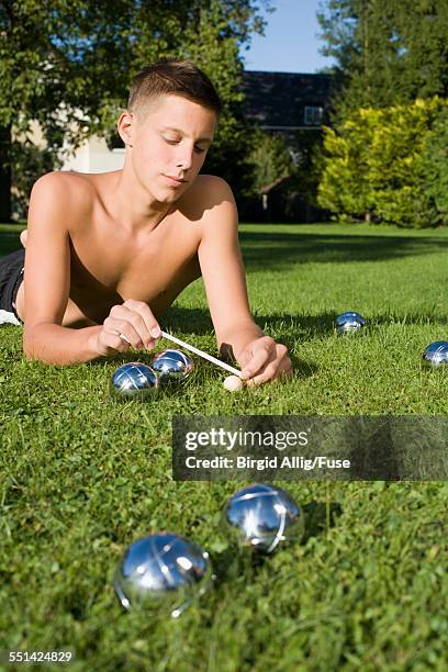 teenage boy measuring distance in game of boules - petanque stock pictures, royalty-free photos & images
