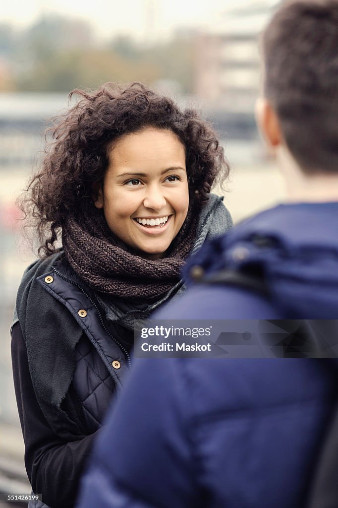 Happy university student woman looking at man outdoors