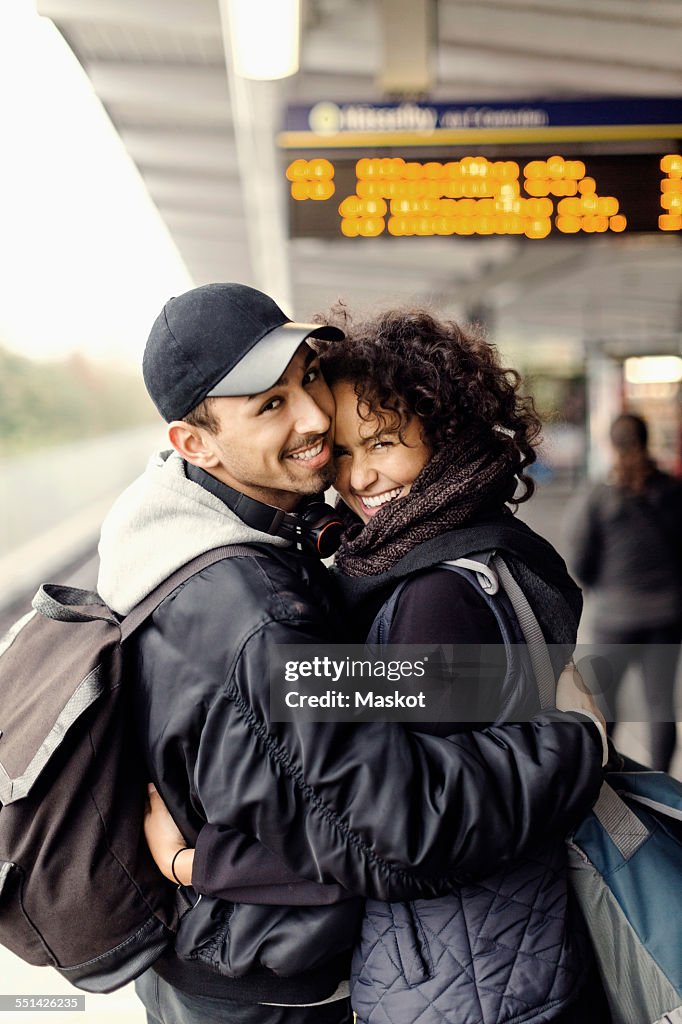 Side view portrait of happy couple embracing on subway platform