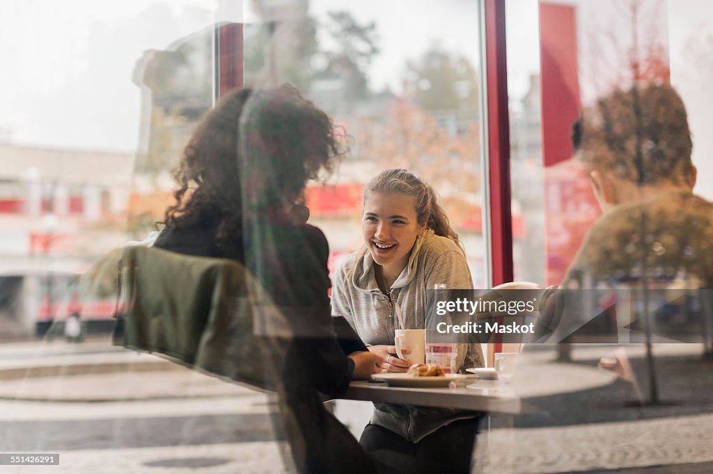 View of happy university students in cafe through glass