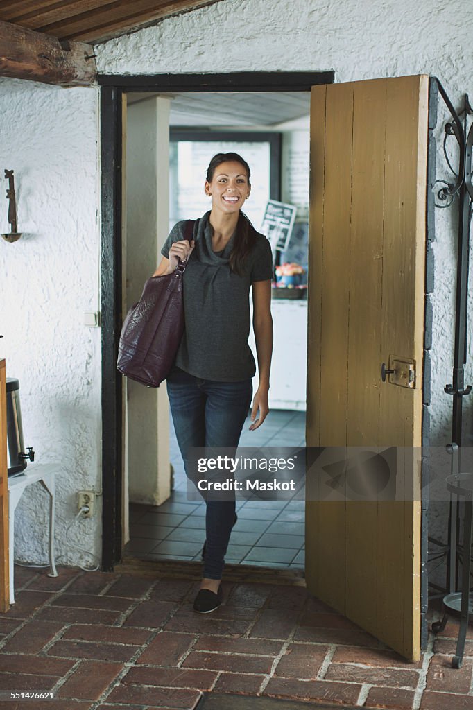 Full length of happy woman entering a house