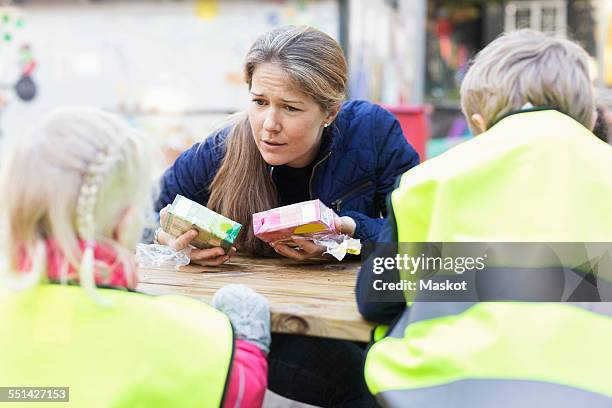 teacher holding juice boxes while communicating with children outside kindergarten - juice box stock pictures, royalty-free photos & images