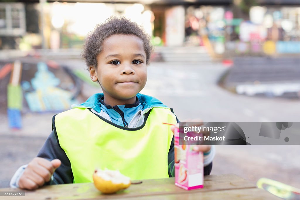 Portrait of boy with juice box outside kindergarten