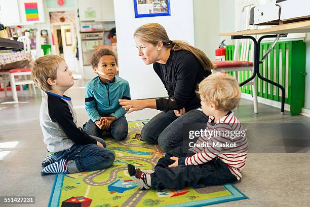 teacher telling story to children in kindergarten - peuterschool gebouw stockfoto's en -beelden