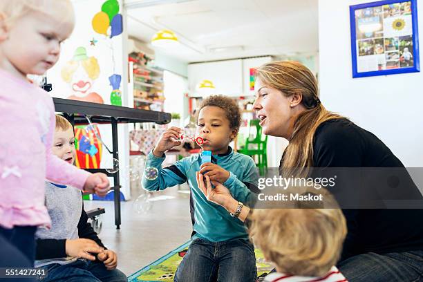 happy teacher and children playing with bubbles in kindergarten - förskolebyggnad bildbanksfoton och bilder