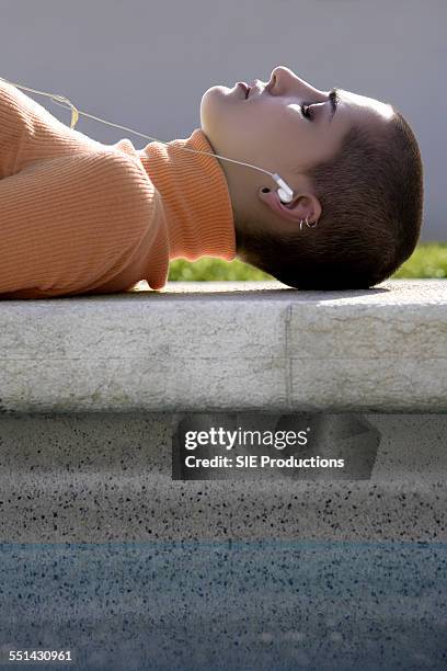 young woman listening to headphones - crew cut stock pictures, royalty-free photos & images