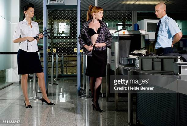 businesswoman removing her shirt at the security check - uitkleden stockfoto's en -beelden