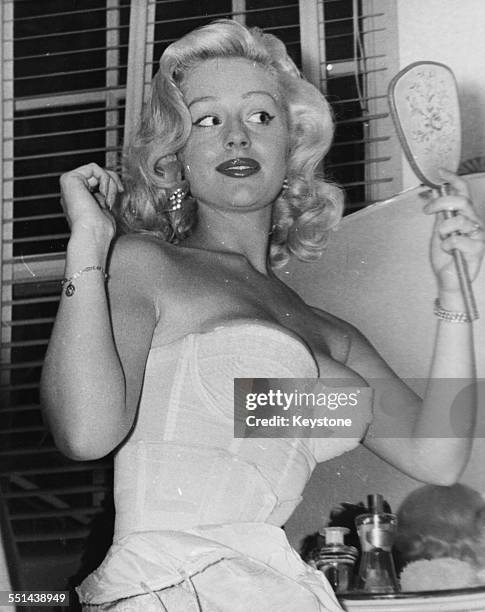 Portrait of actress Sheree Winton wearing a corset and looking in a hand held mirror, at her home in Sheffield, July 24th 1958.