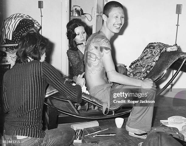 Japanese fashion designer Kansai Yamamoto having his back painted by assistants, at his Boston 151 boutique on Fulham Road, London, May 12th 1971.