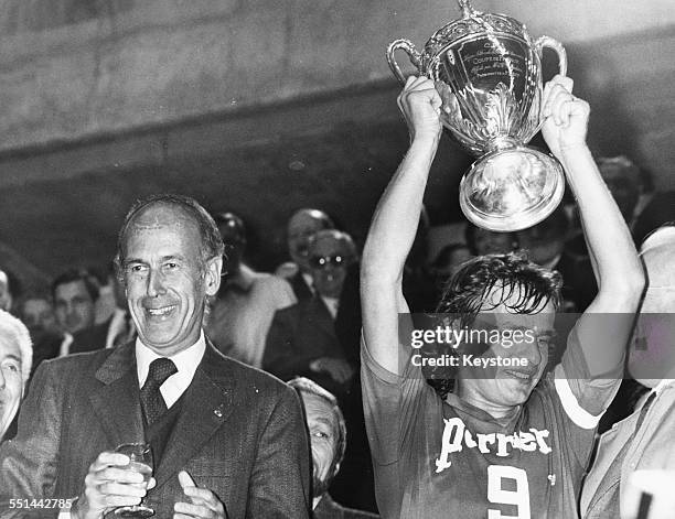 French President Valery Giscard D'Estaing celebrating with football player Georges Bereta, captain of Saint Etienne Football Club, holding the Coupe...