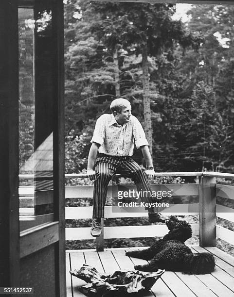 Portrait of Russian poet Yevgeny Yevtushenko relaxing on the balcony of a country house with his dog 'Datcha', January 15th 1973.