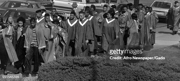 The Armstrong High school choir, boys and girls in a large group wearing robes and walking along a road, Baltimore, Maryland, March 18, 1993.