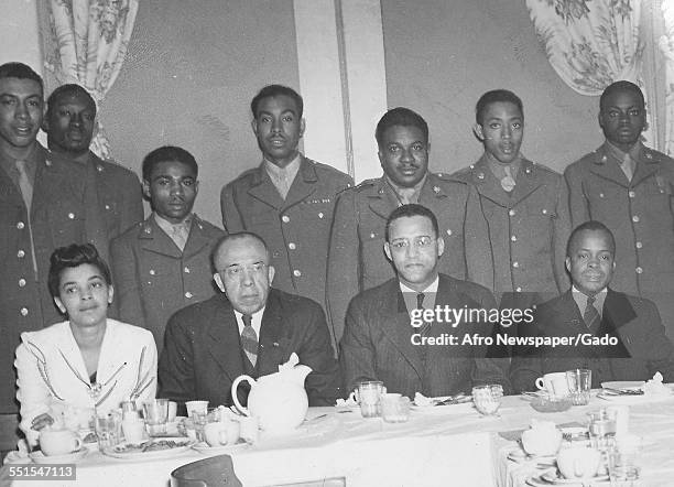 Group of African-American military men, soldiers in uniform and people seated at a table, the United Services Organization, February 24, 1945.