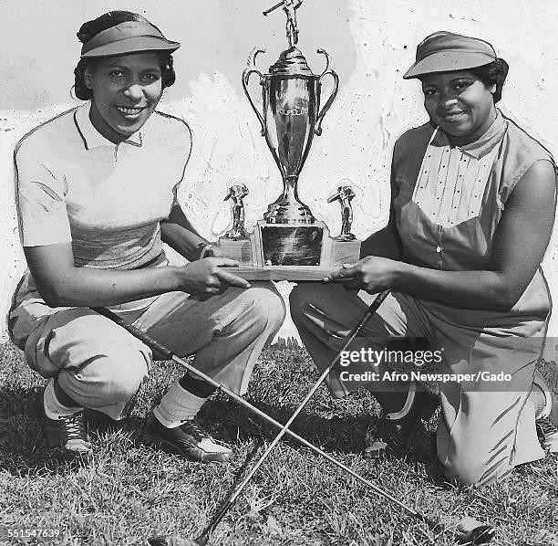 Two women, Sarah Smith and Ethel Finch, posing with a large trophy they won at the Wake Robin golf club, an African-American golf club in Washington...