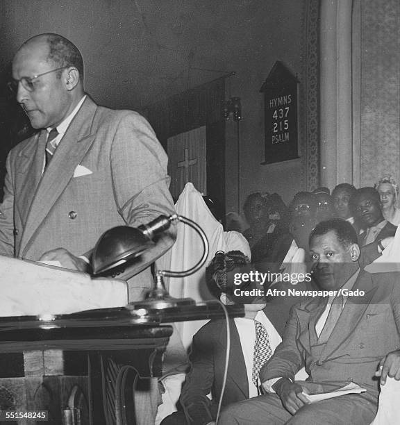 Max Yergan, president of the National Negro congress addressing a meeting in the Metropolitan AME church, observed by Paul Robeson and Albert...