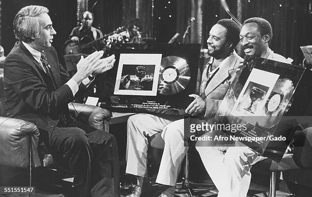 Grover Washington, An African-American jazz-funk and soul-jazz saxophonist, on a television show holding a framed album award, 1985.
