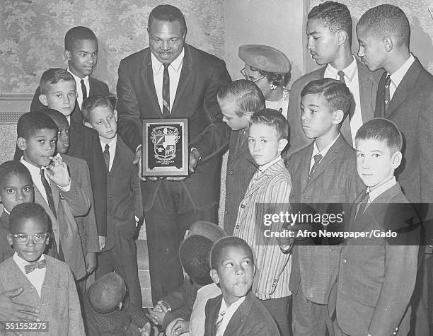 Archie Moore, African-American professional boxer and the Light Heavyweight World Champion, giving out awards to young people, November 4, 1961.