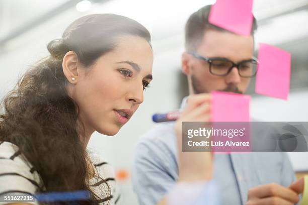 business people writing on adhesive notes - genomskinlig skrivtavla bildbanksfoton och bilder