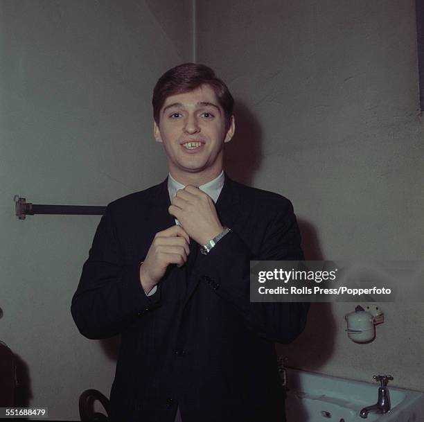 English singer and keyboard player, Georgie Fame pictured adjusting his tie in a dressing room backstage circa 1964.