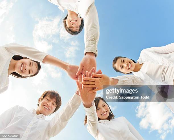 young friends stacking hands - hand stack stock pictures, royalty-free photos & images