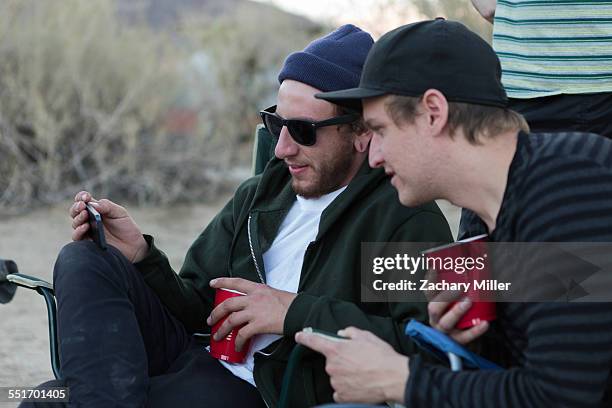 two young male friends looking at smartphone on campsite, anza-borrego desert state park, california, usa - cell mates stock-fotos und bilder