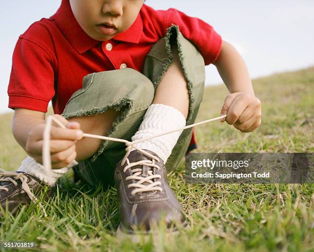 boy tying shoelace - boy tying shoes stock-fotos und bilder