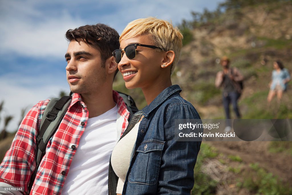 Young couple, outdoors, looking at view, friends trailing behind