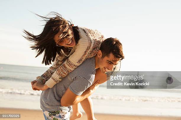 young couple fooling around on beach - couple fun stock pictures, royalty-free photos & images