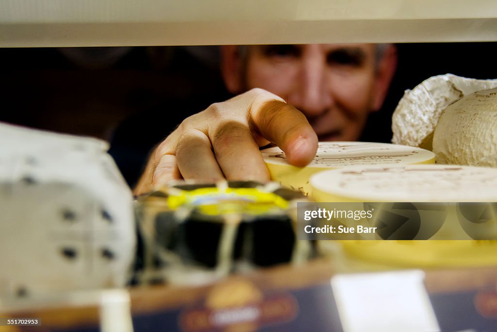 Cheesemonger arranging cheese in display