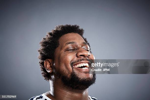 close up studio portrait of mid adult man laughing - black people laughing stock-fotos und bilder