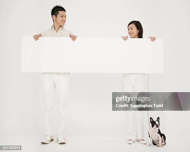 happy couple holding blank placard with their dog - couple placard stock pictures, royalty-free photos & images