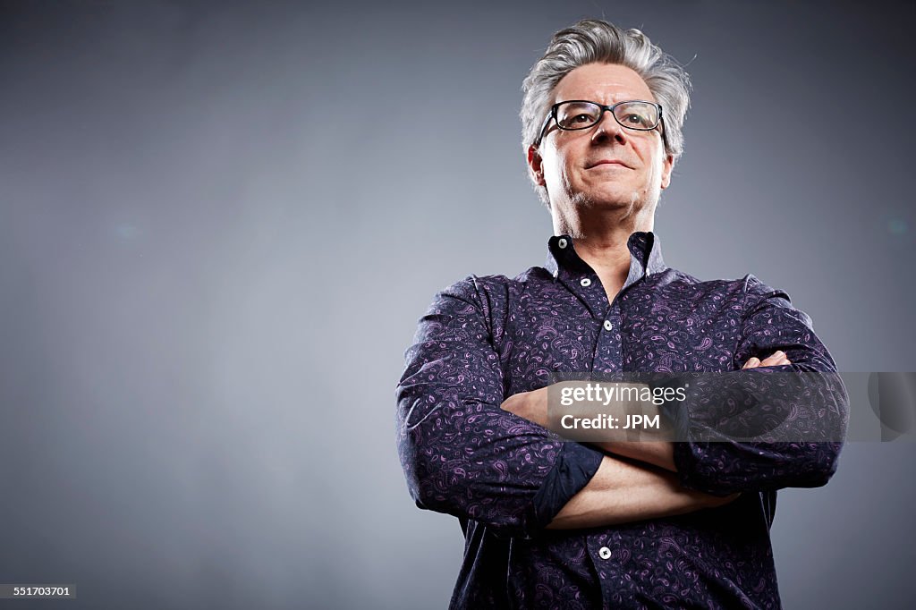 Low angle studio portrait of mature businessman with arms folded