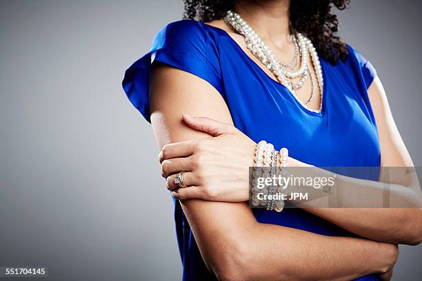 cropped studio shot of mature woman with arms folded - bracelet stock pictures, royalty-free photos & images