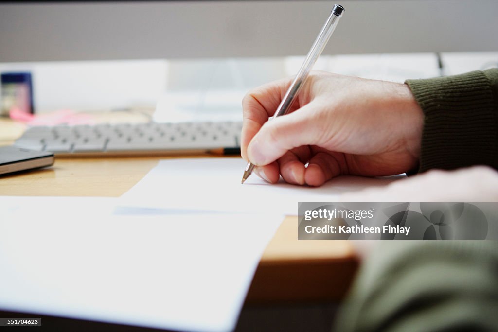 Man writing on paper with pen