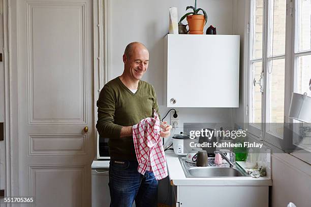 mature man drying glass at kitchen sink - torchon photos et images de collection