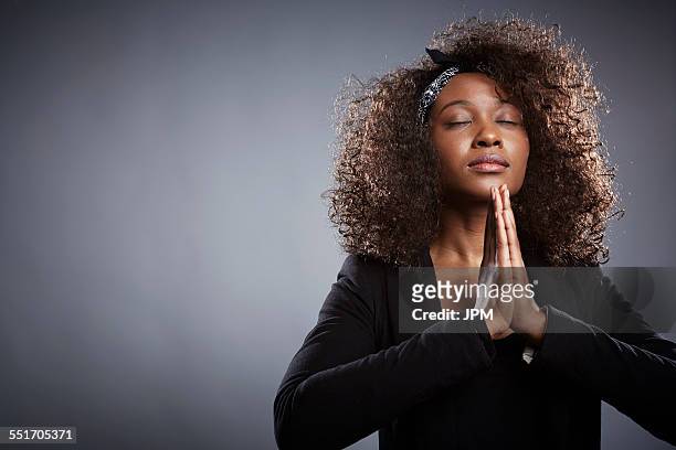 studio portrait of young businesswoman praying - black women praying stock pictures, royalty-free photos & images