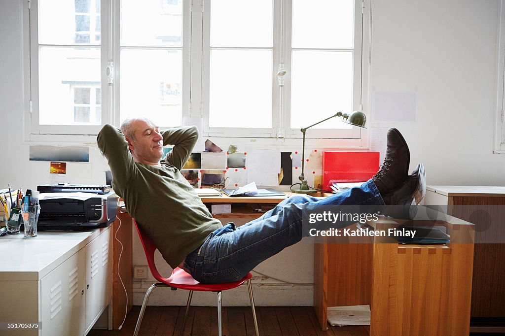 Mature man sitting with feet up at desk