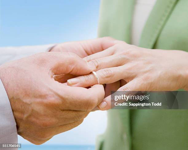 man putting ring in womans finger - putting ring on finger stock pictures, royalty-free photos & images