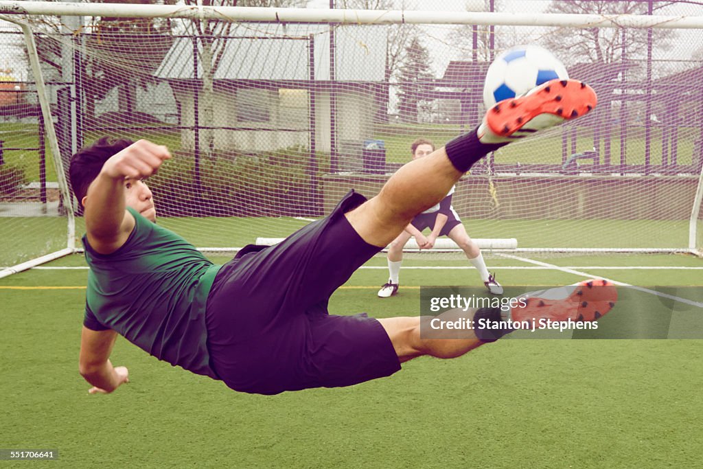 Young male soccer player kicking ball toward goal