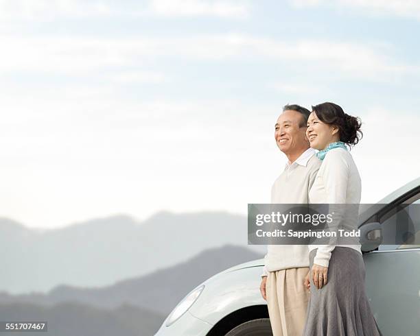 couple overlooking the distant standing near the car - 夫婦 ストックフォトと画像