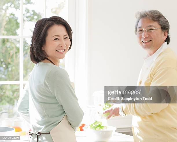mature couple in kitchen - schürze mann rückansicht stock-fotos und bilder