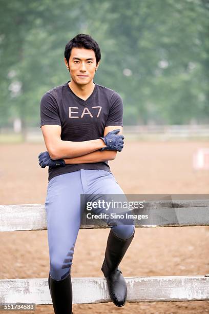 young man sitting on the fence - 馬の衣装 ストックフォトと画像