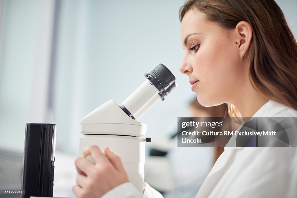 Female science student using microscope