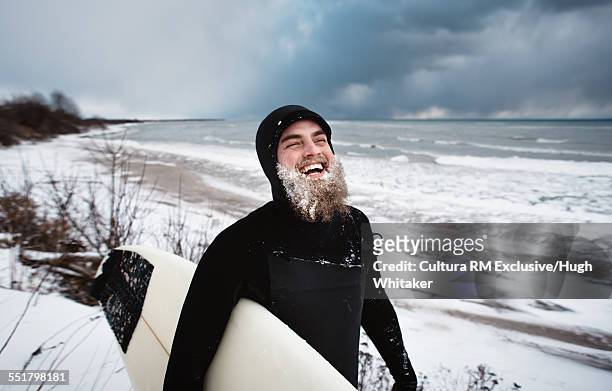 laughing surfer with beard, beside lake ontario in winter - adventure　sea stock-fotos und bilder