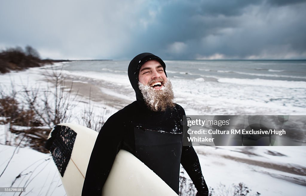 Laughing surfer with beard, beside Lake Ontario in winter