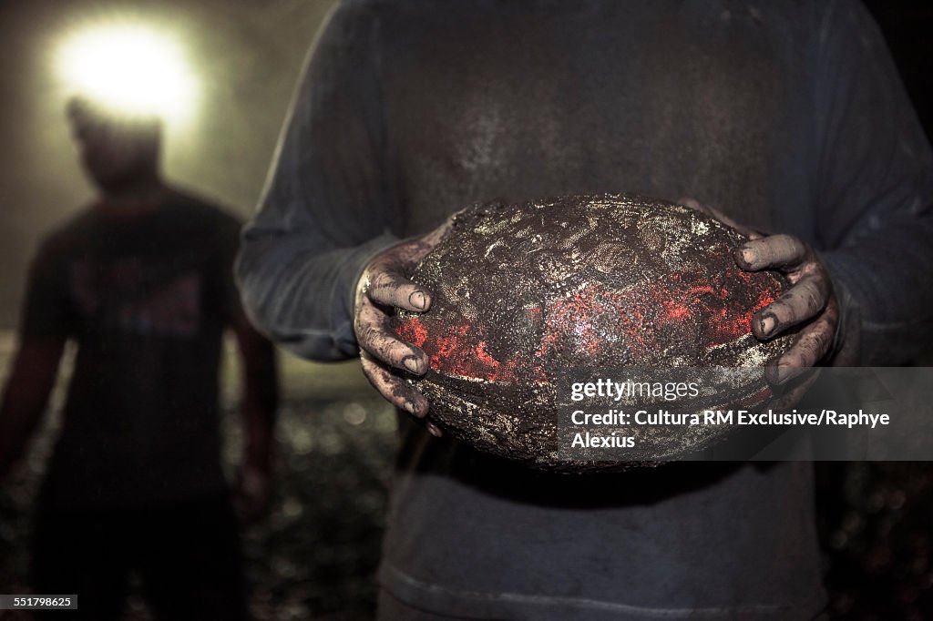 Close up of muddy ball in rugby players hands